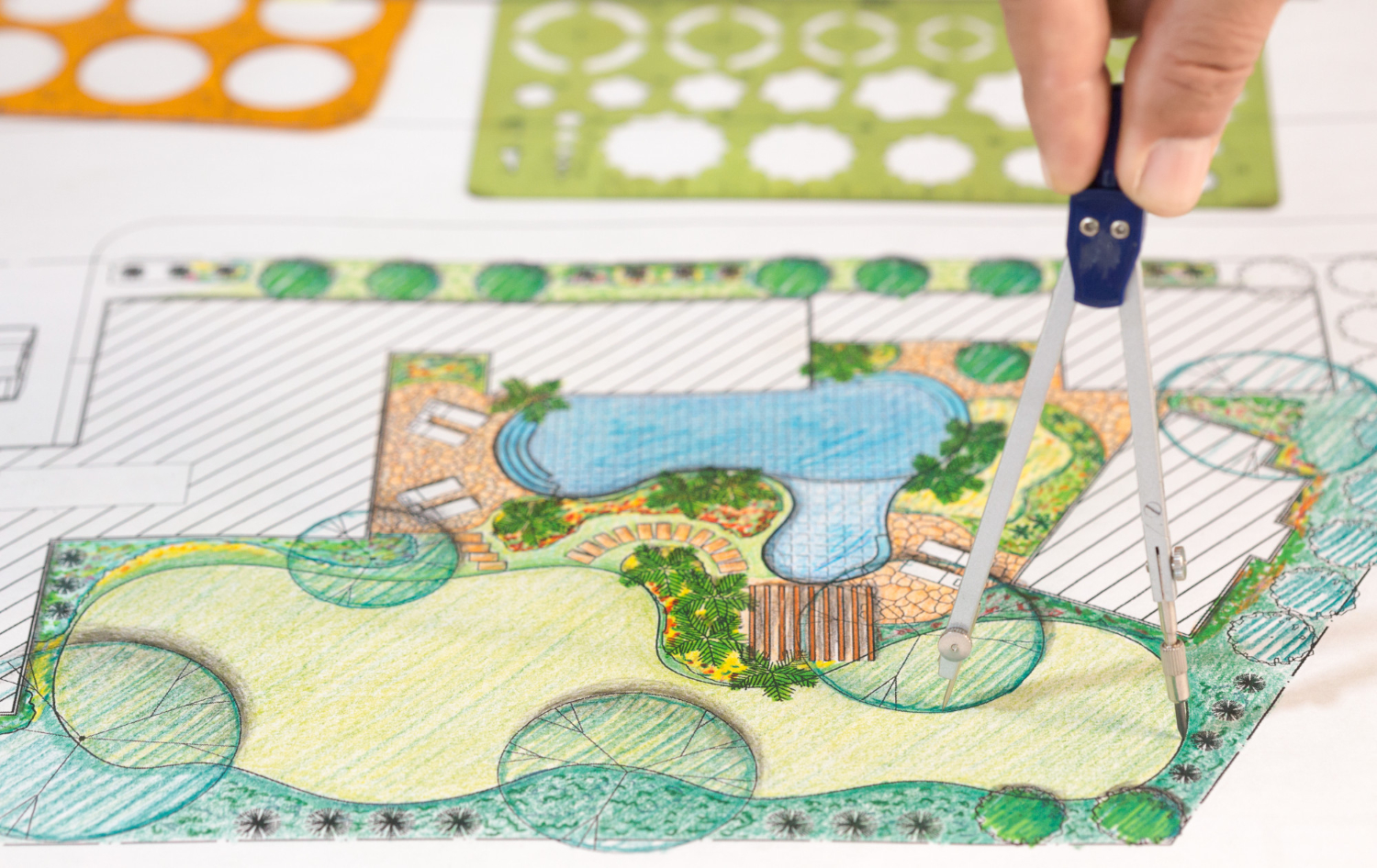 Person designing a landscape with a pencil and colors